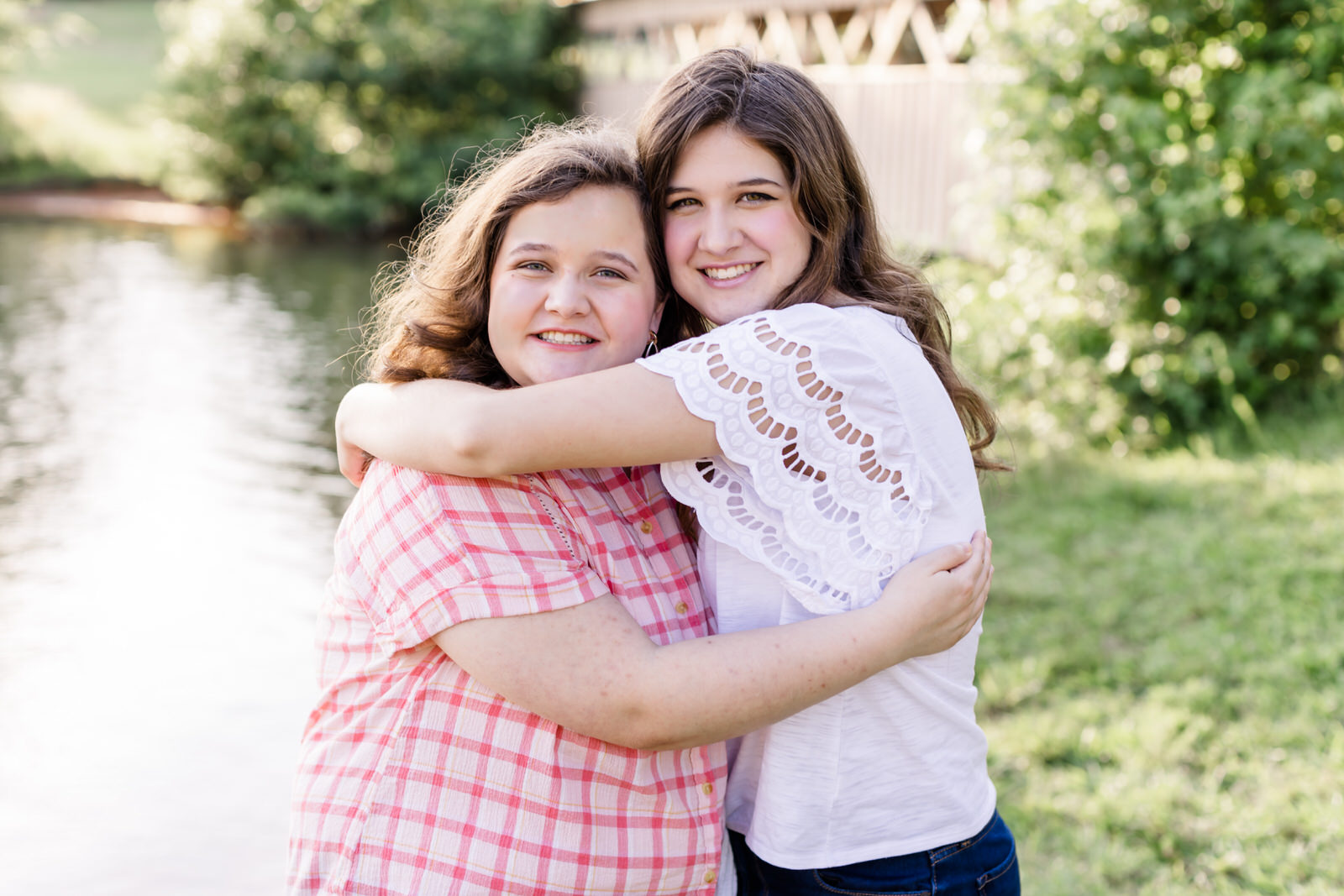 Two teenage sisters hug each other in front of an old covered bridge in Gainesville, Georgia