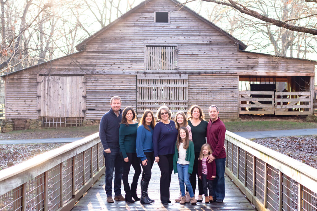 An extended family stands in front of an old wooden barn in Duluth, Georgia