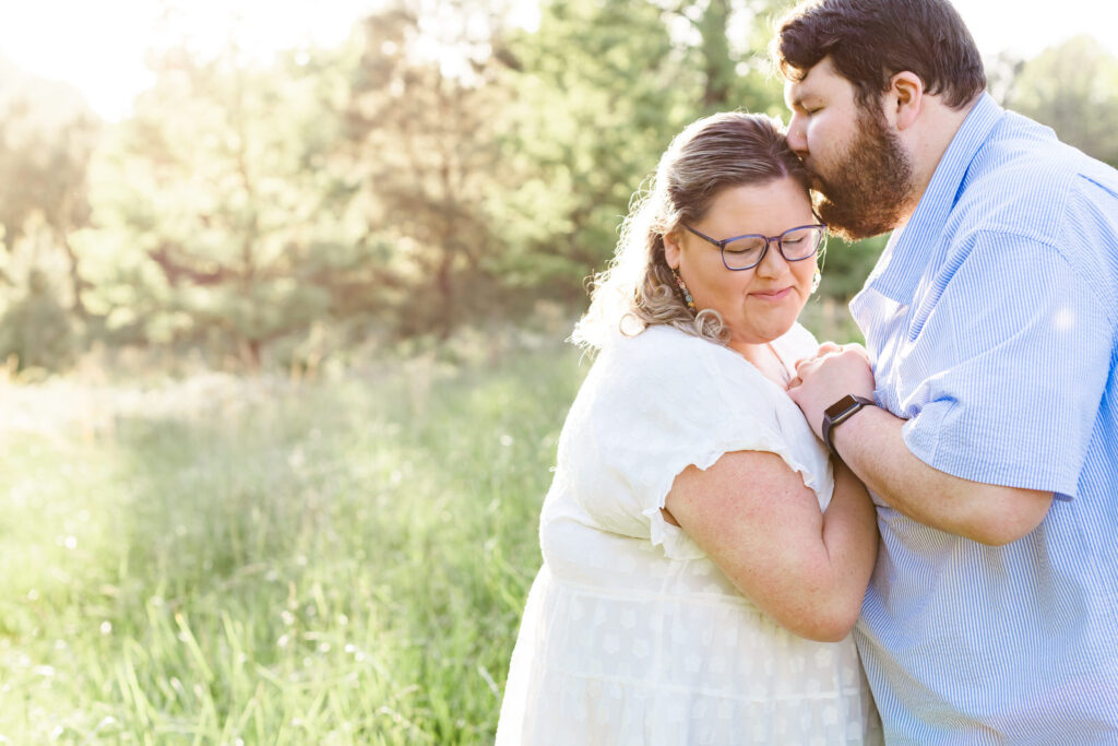 An engaged couple embrace in a field of tall grass in Dacula, Georgia.