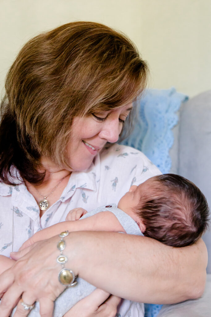 Grandma looks down at newborn grandson and smiles at him during lifestyle newborn session in Gwinnett County, Georgia